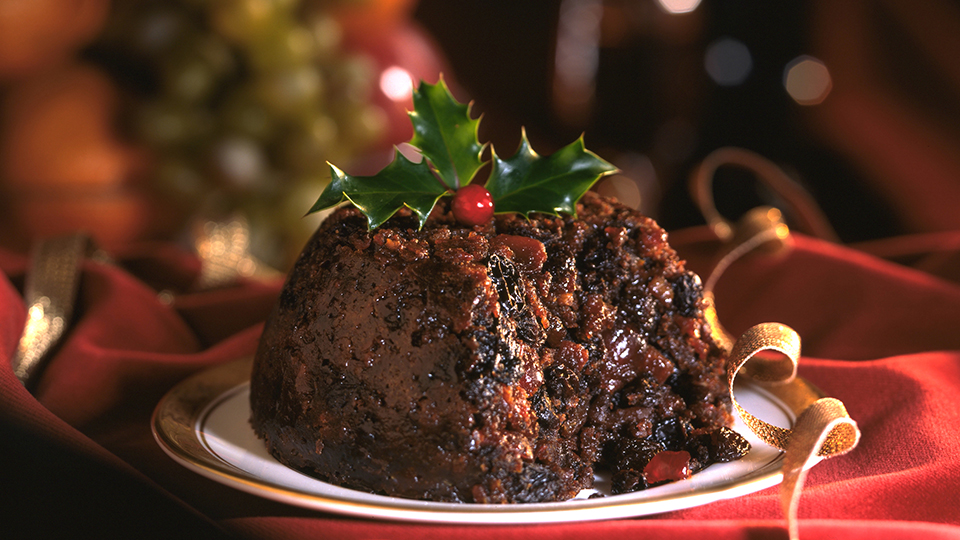 photo of Christmas pudding on a table with holly on top 