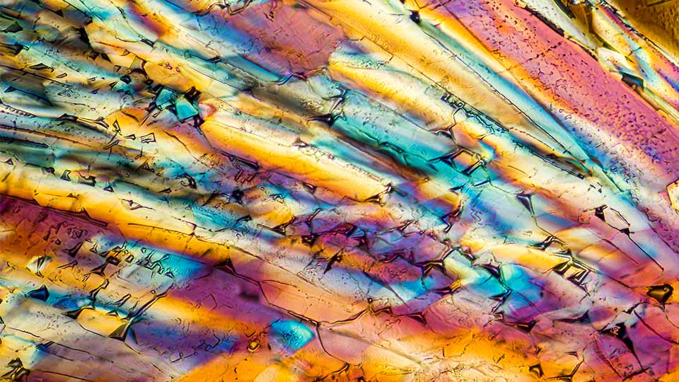 Close-up of the striking, iridescent colours of a liquid crystal composed of rod-like molecules. 