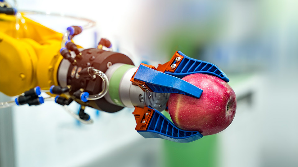 A robot hand holding an apple
