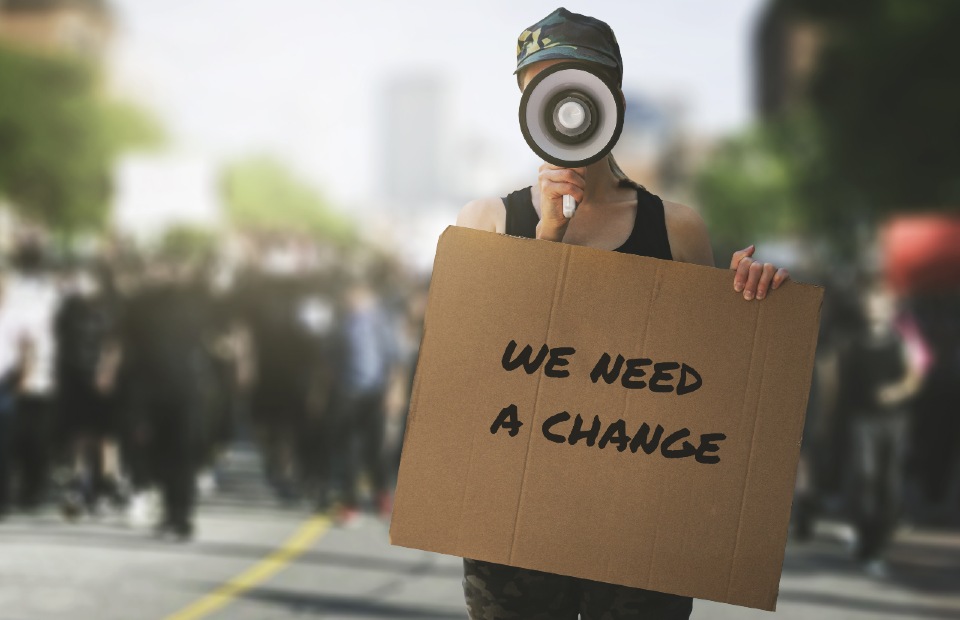 Woman holding 'we need a change' sign. Getty