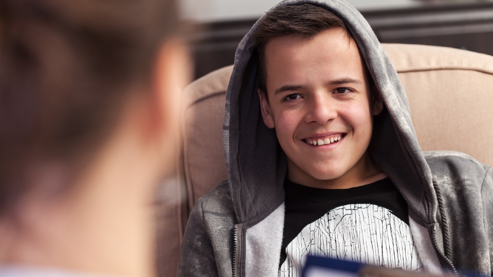 Young man in a hoodie talking to an adult. 
