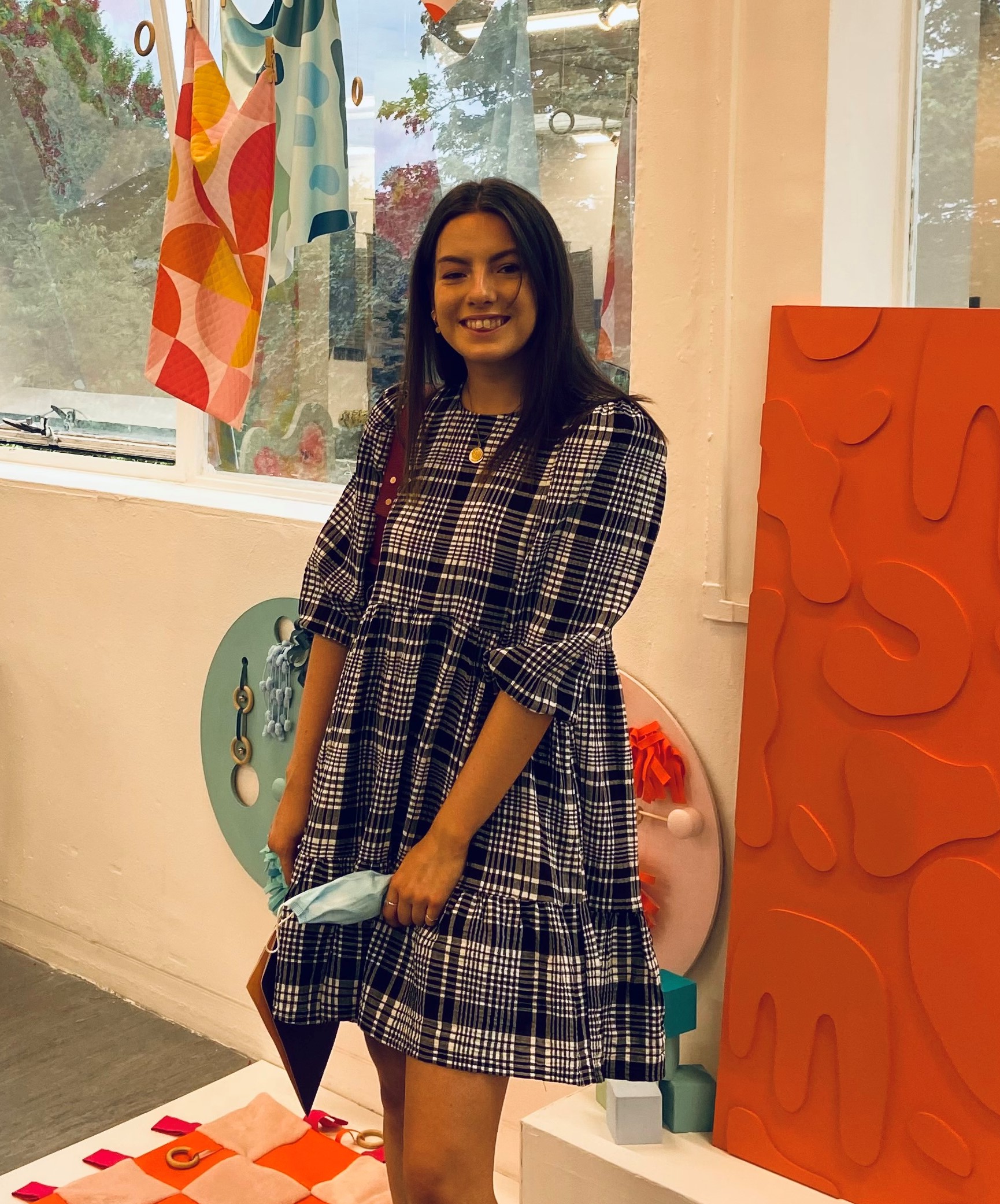 Photo of student Ella Forrest standing in front of her work at the University's Creative Arts degree show