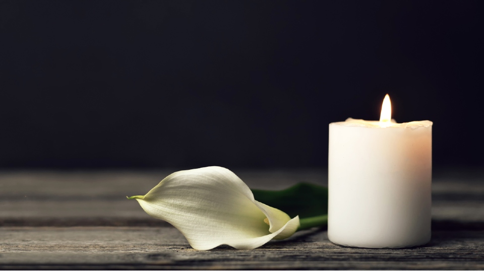 Image of a candle next to a flower 