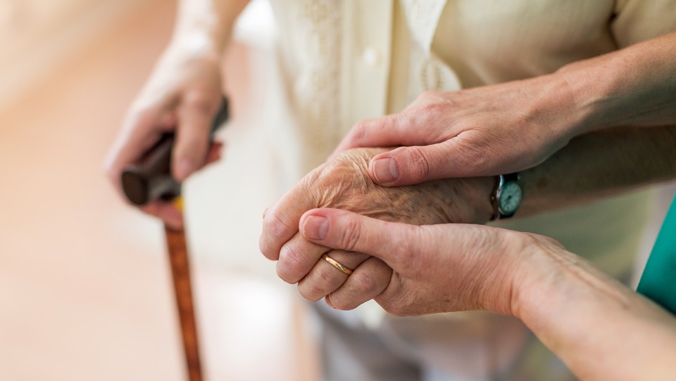An elderly person is supported by a care worker