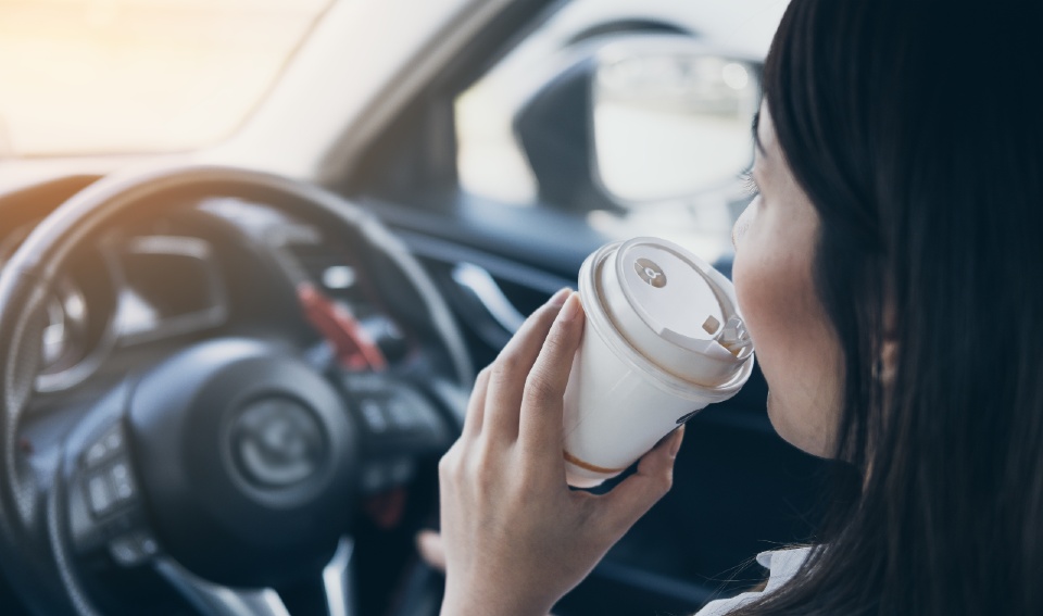 Woman driving a car with a cup of coffee in her hand 