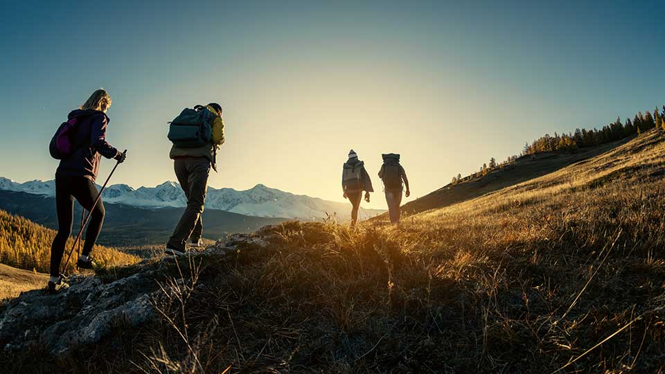 People hiking over hills during sunrise