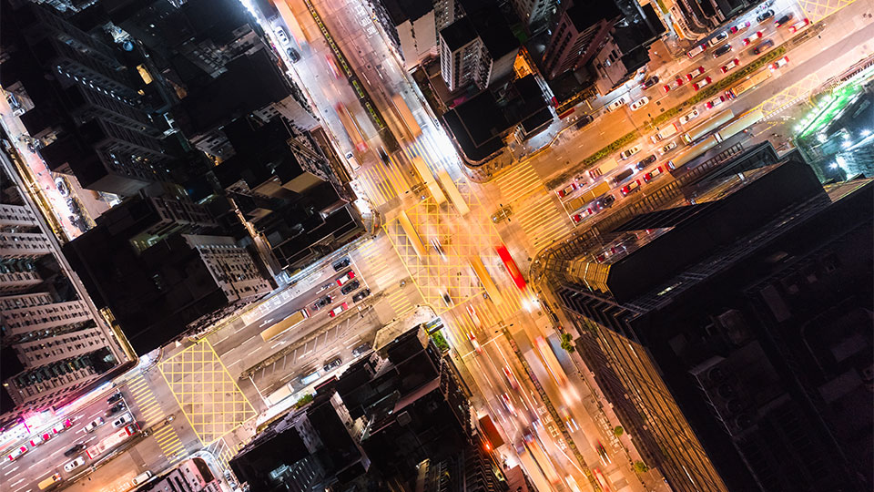 A top-down view of a busy crossroads junction in an urban environment at night
