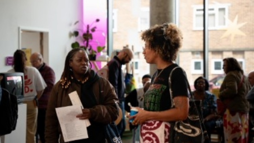 Two people stood chatting inside an arts exhibition