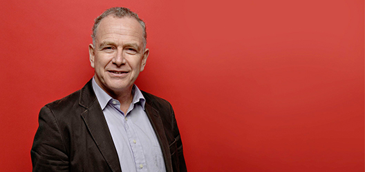 photo of Professor Alistair Milne with a red background