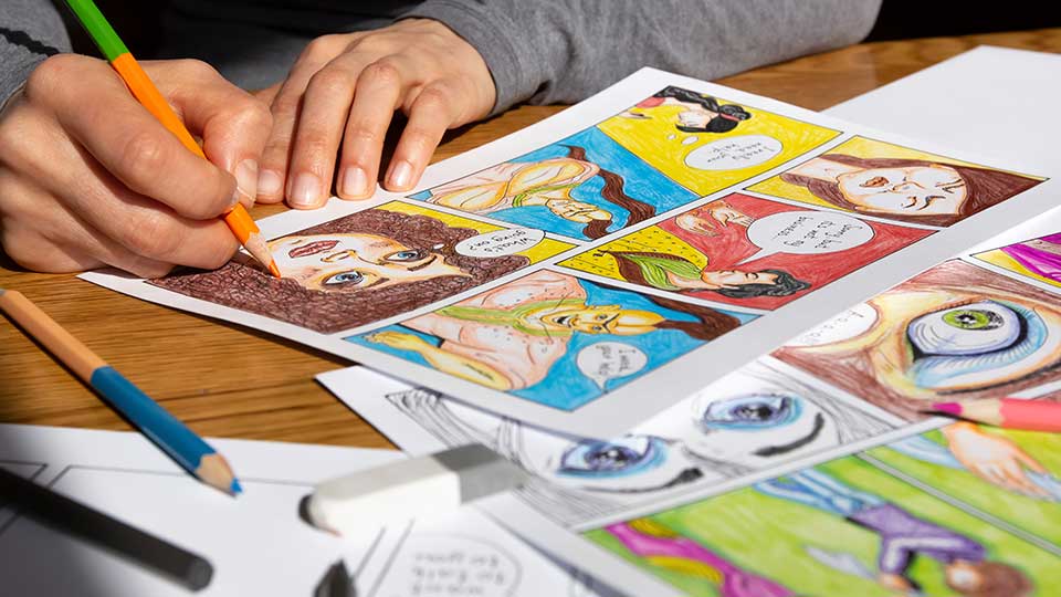 Person seated at a table working with colorful craft materials during a hands-on workshop.