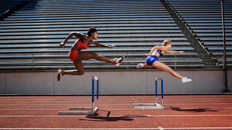 Women jumping over hurdles