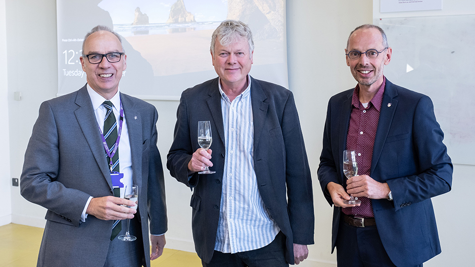 photo of Professor Steve Rothberg, Professor Rob Haslam and Professor Cees De Bont at celebratory event with glasses of champagne 