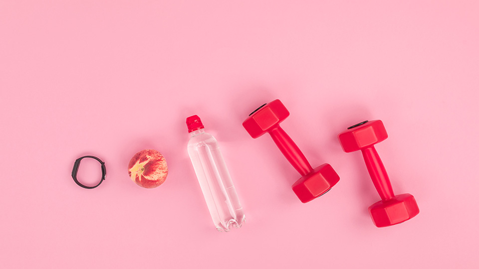 Pictured are workout weights, a bottle of water and a peach. 