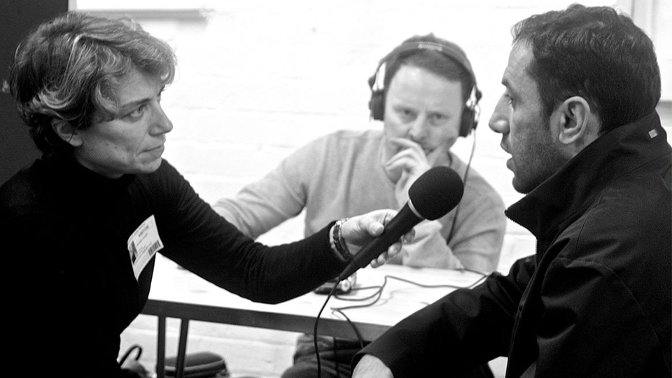 black and white photo of Dr Antonia Liguori interviewing someone and holding a microphone.