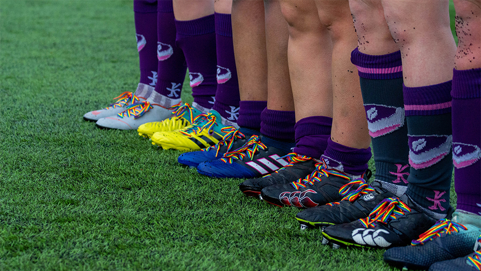 photo of sport players' legs/feet in a row wearing rainbow laces on trainers