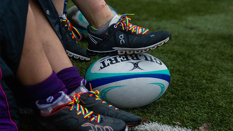 photo of players wearing rainbow laces with one trainer rested on rugby ball 