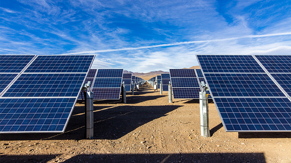 Photo of solar panels in an arid region with blue skies