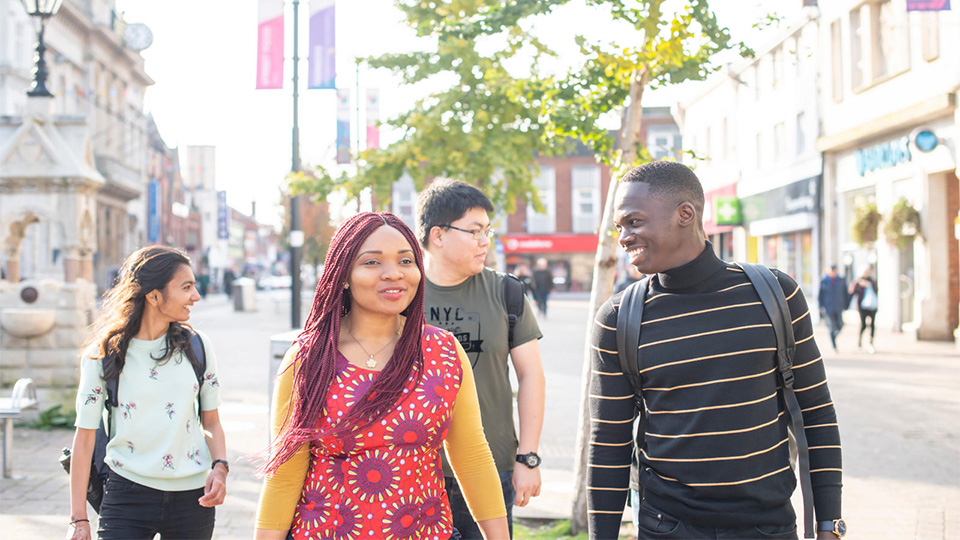 photo of four students walking and laughing together in town