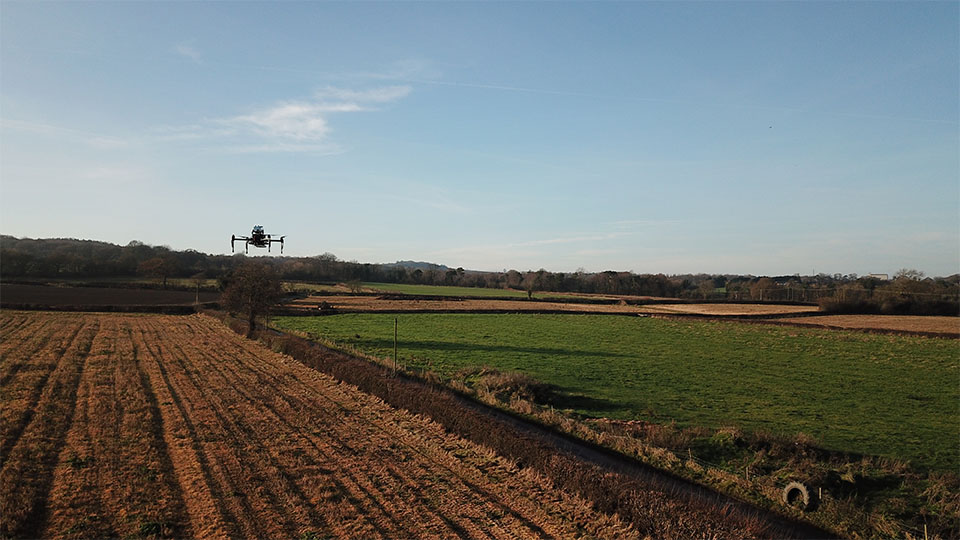 A photo of a drone in the air over a field