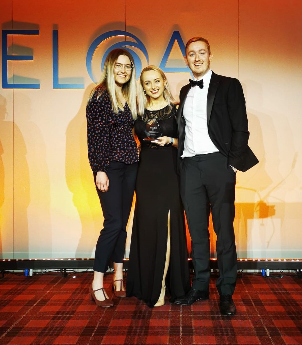 Photo of two staff members at the HELOA Awards holding an award