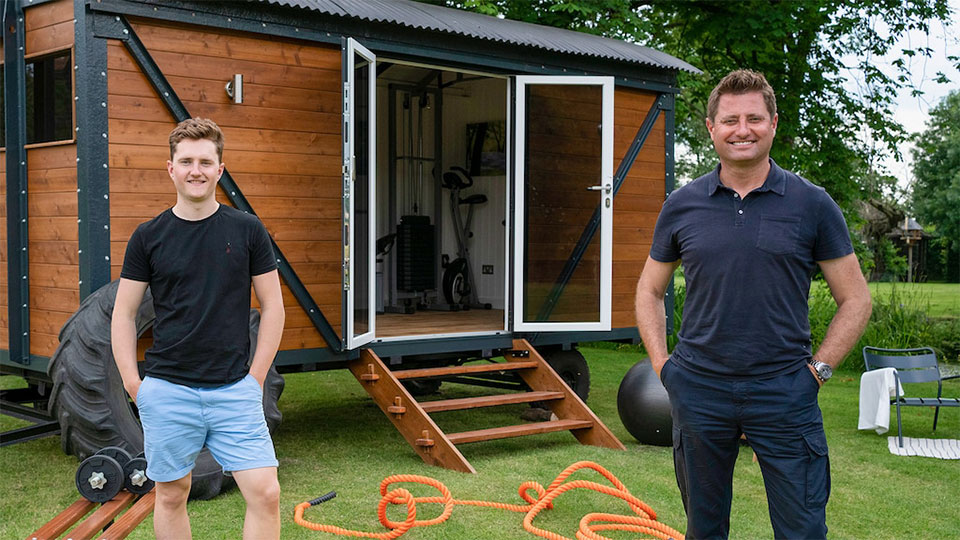 Lewis Naughton and George Clarke in front of converted railway carriage