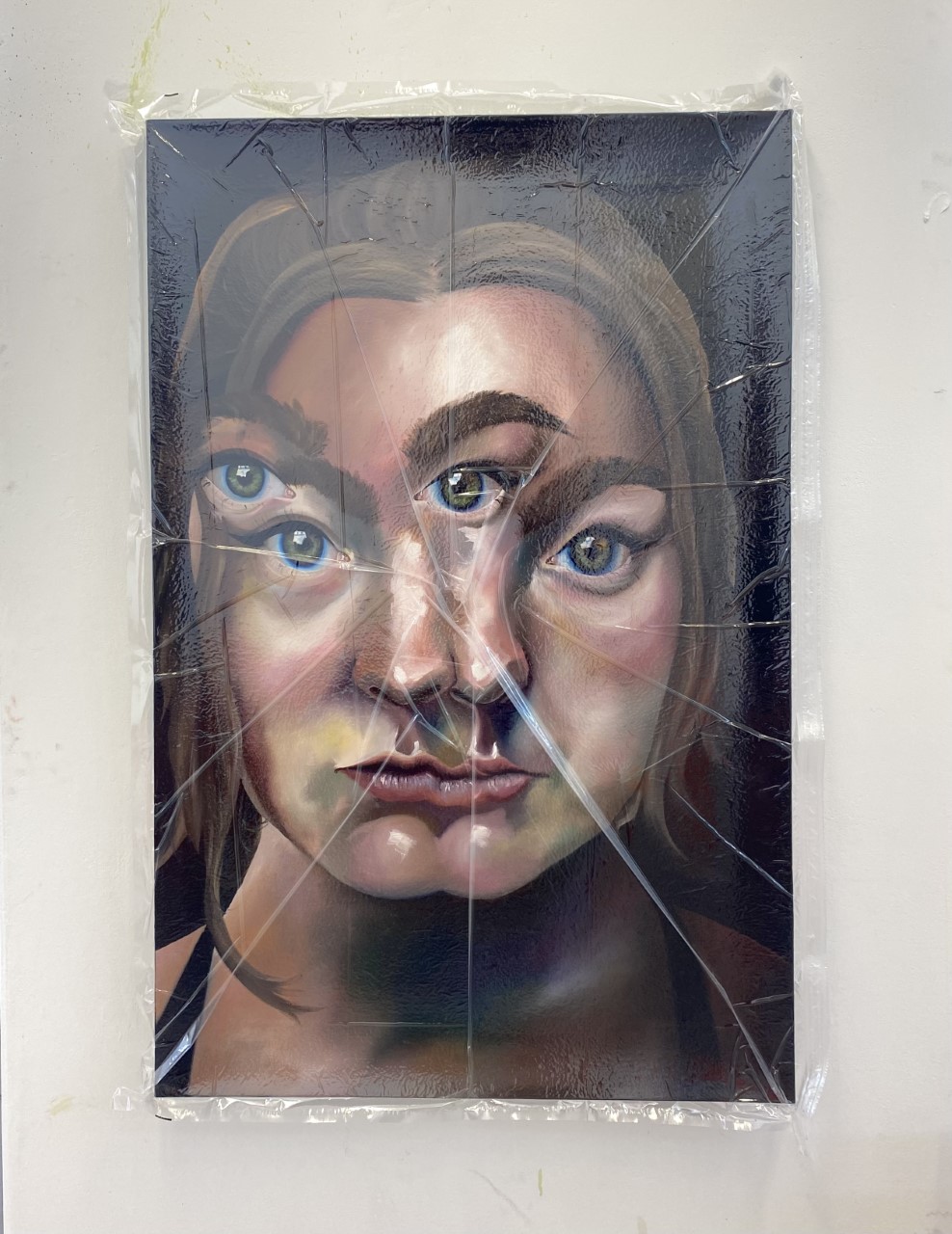 Image of oil painting on a canvas by graduate Poppy Smith. Painting is of a women's face that appears to be distorted by a smashing mirror effect