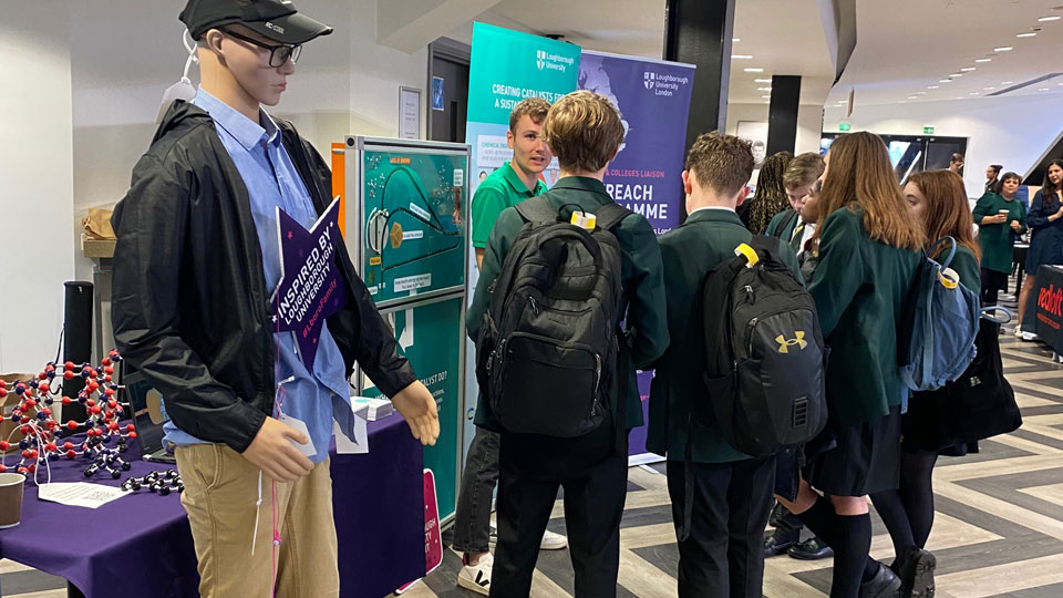 A group of school children talking to one of the PhD researchers at the SlowCat exhibition stand