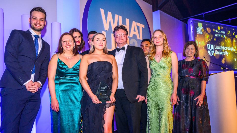 Photo of colleagues from Loughborough University collecting the 'Facilities' award on stage, looking down into the camera