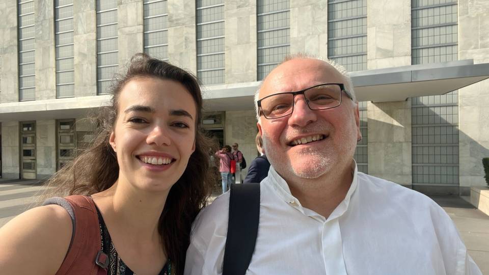 Close-up photo of two Loughborough staff smiling outside of the United Nations Headquarters in New York.