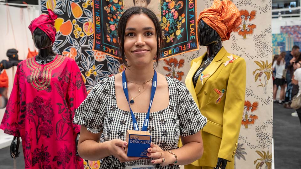 Photo of student Peace Rodliff holding the Tu Clothing Creative Pattern and Print Award trophy in her hands and smiling straight on at the camera