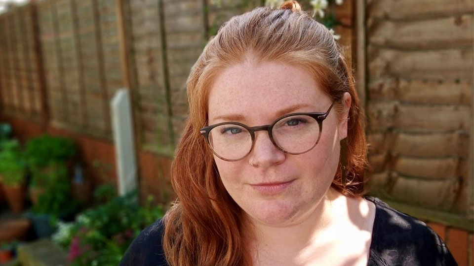Headshot of a person with ginger hair and glasses