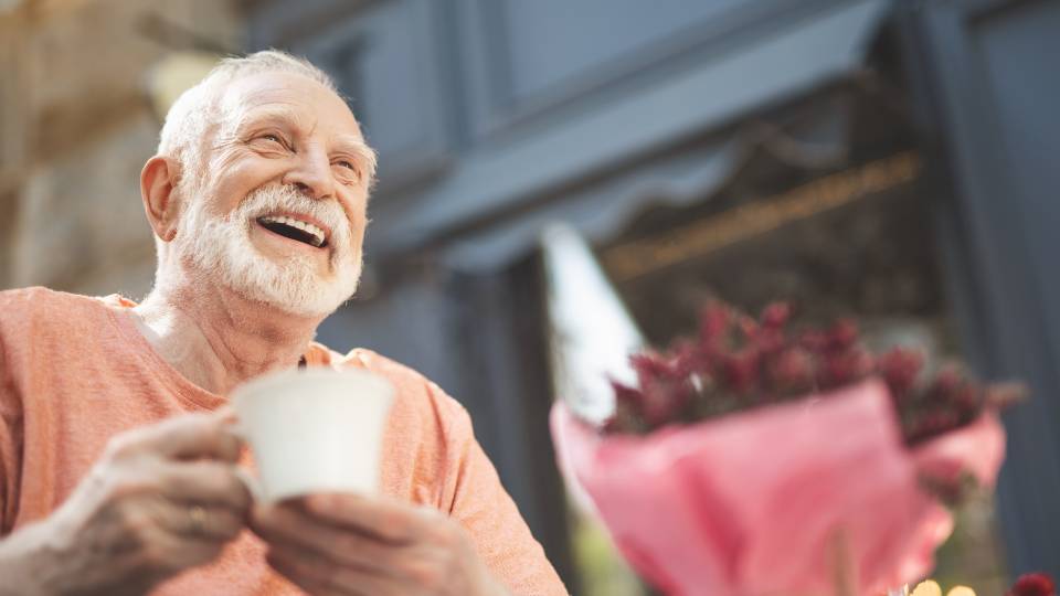 a man with a hot drink,  smiling to the camera