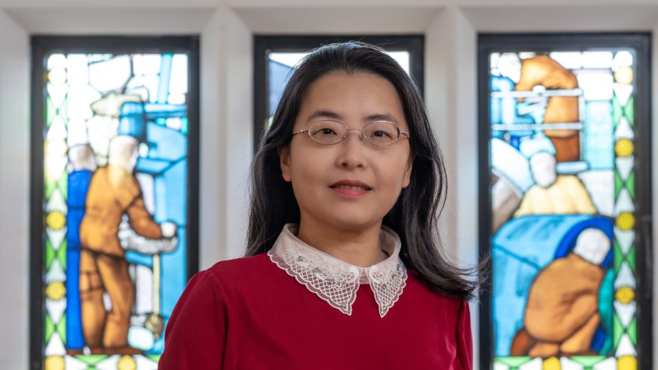Diwei Zhou in front of stained glass windows.