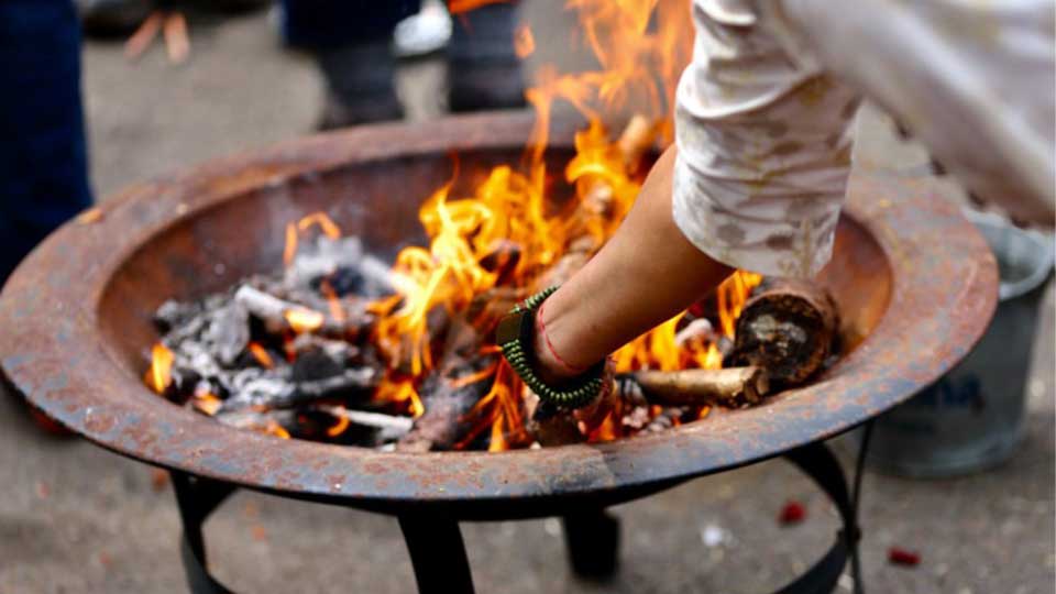 A person's hand reaching toward an outdoor fireplace.
