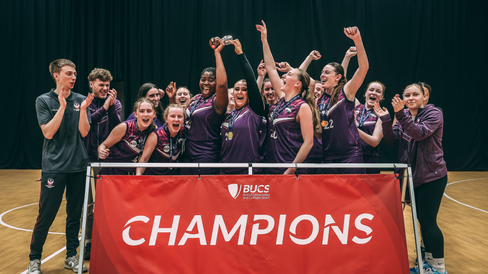 Loughborough basketball players lifting a trophy and celebrating.