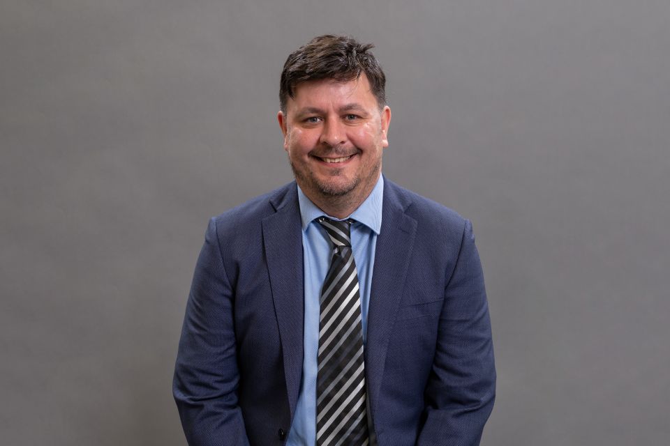 Close-up of Professor Dan Parsons in front of a grey background.
