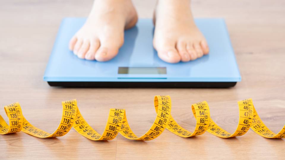 a person standing on weighting scales with a measuring tape laid in front