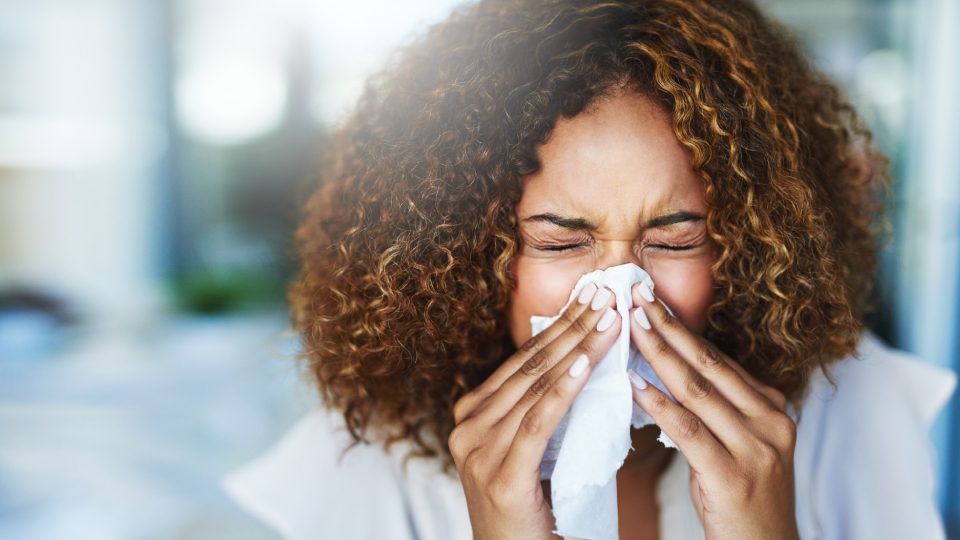 a woman sneezing into a tissue