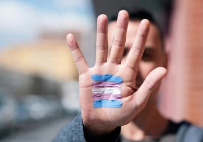An outstretched palm with the flag of transgender solidarity painted onto it