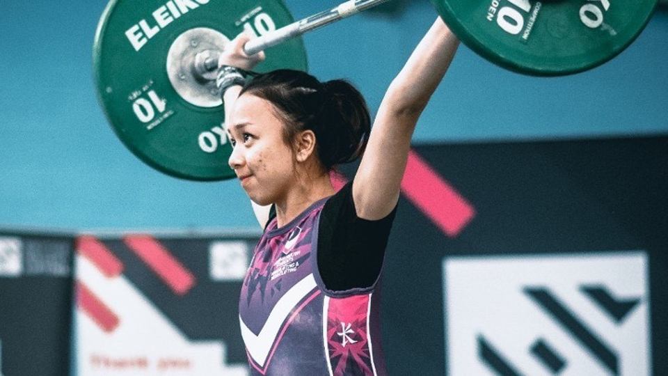 Photo of Syuhaidah Ahman lifting a barbell above her head, with camera taking photo from the side