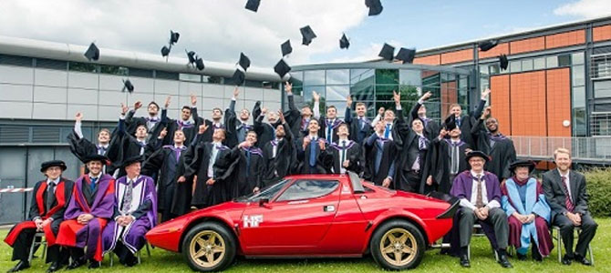 Class of 2015 standing with lecturers sitting down around a sports car
