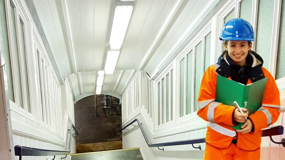 Female student wearing a high vis suit with a helmet in a tunnel.