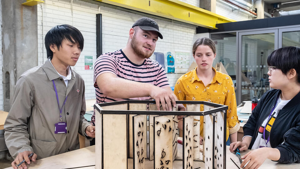 Four students in a design studio working on an architectural model.