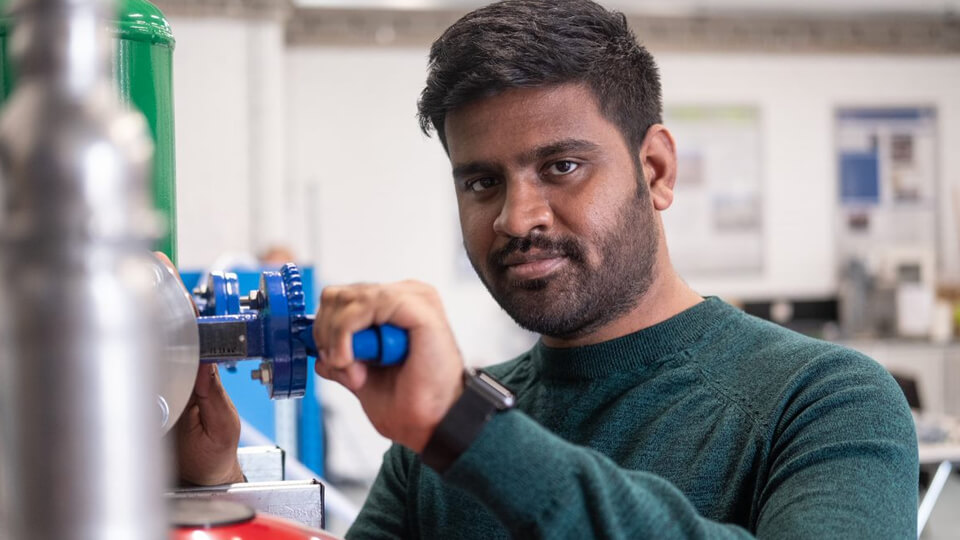 Male student in a green jumper looking at the camera while working on equipment in the BISPA lab.