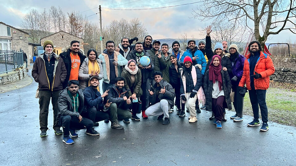A group of students taking a group photo outside in winter clothes.