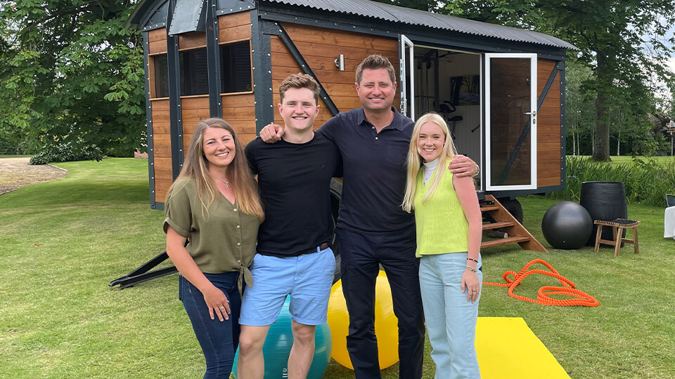 Student Lewis stood in front of his renovated railway carriage with two of his friends and George Clarke.