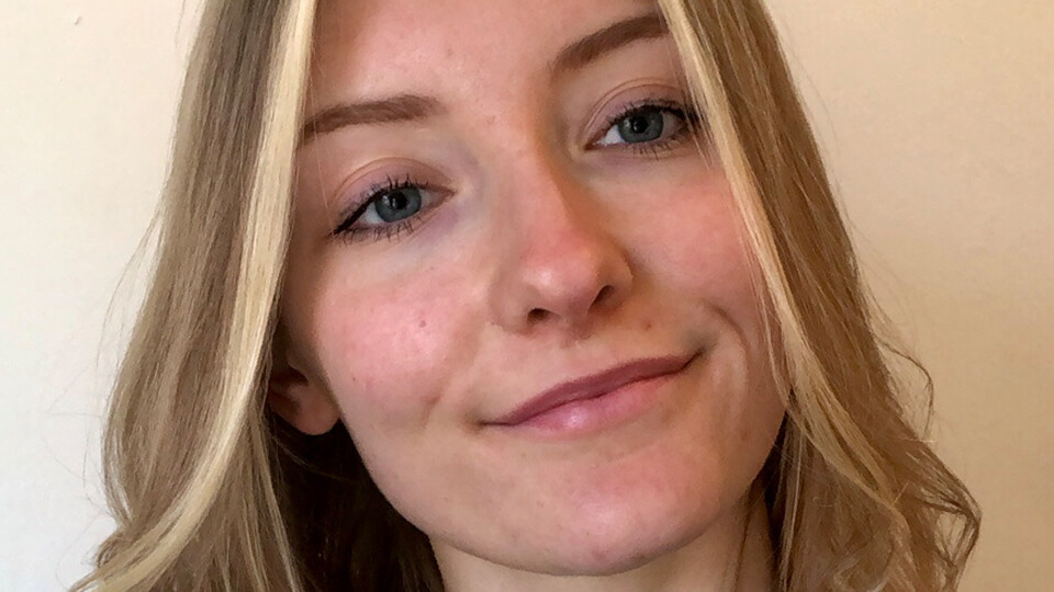Female student smiling at the camera in front of a light background.