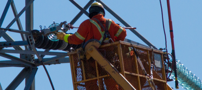 Technician in a cherry-picker, repairing a pylon