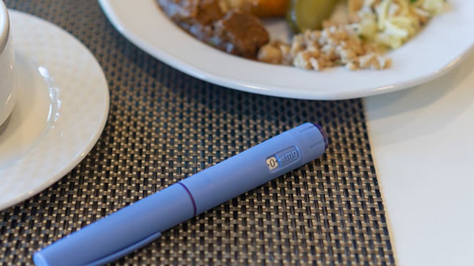 GLP1 pen on a table surrounded by food