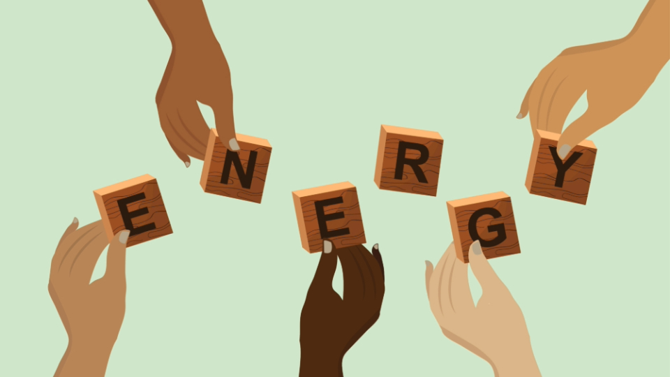 Hands holding wooden blocks that spell the word 'energy' against a pale green background.